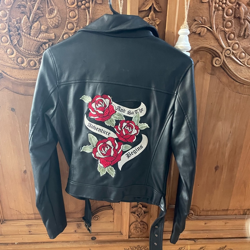 Leather jacket with flowers, belt, quote, and zips up